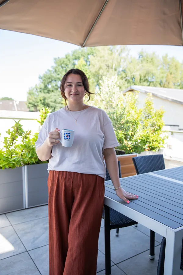 Mitarbeiterin mit Kaffeetasse auf der Terrasse des Betriebsgebäudes