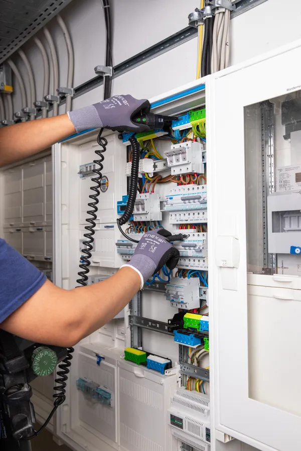 Elektroniker verdrahtet eine Verteileranlage im bewohnten Bestand