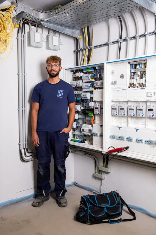 Elektroniker vor einer fertig verdrahteten Zählerplatzanlage